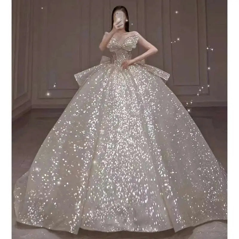A shimmering white one-shoulder wedding dress with long trailing heavy industry sequin bodice and off-the-shoulder design