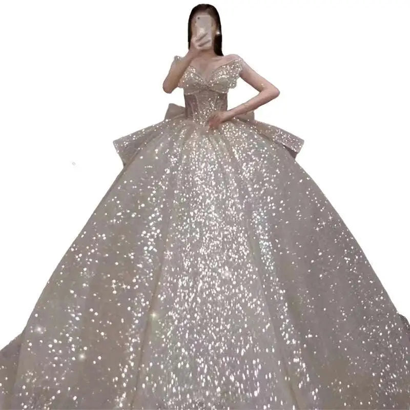 A shimmering silver sequined one-shoulder wedding dress with a fitted bodice and long trailing heavy skirt