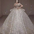 A shimmering white one-shoulder wedding dress with sequins and a fitted bodice featuring a long trailing heavy design