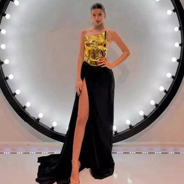 One-shoulder slit mop black dress two-piece set with glossy gold metallic bodice and flowing black satin skirt with high slit