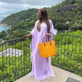 Vibrant orange woven tote bag with brown leather handles complements the orange feathered loose dress luxury robe collection