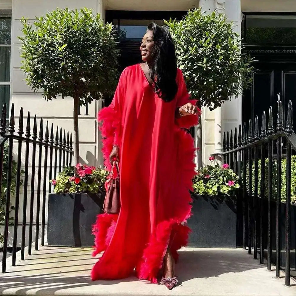 A vibrant red dress luxury robe featuring voluminous orange feathered loose sleeves and hemline for elegant wear