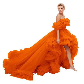 A vibrant orange luxury women’s fashion high low gown with off the shoulder voluminous ruffles and flowing train