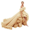 A flowing champagne-colored off-the-shoulder tulle high low gown with layered ruffles for luxury women’s fashion
