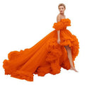 A vibrant orange luxury women’s fashion high low gown with layered ruffles and a flowing train for evening wear