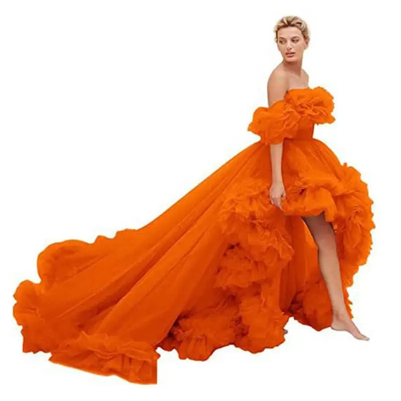 A vibrant orange luxury women’s fashion high low gown with layered ruffles and a flowing train for evening wear