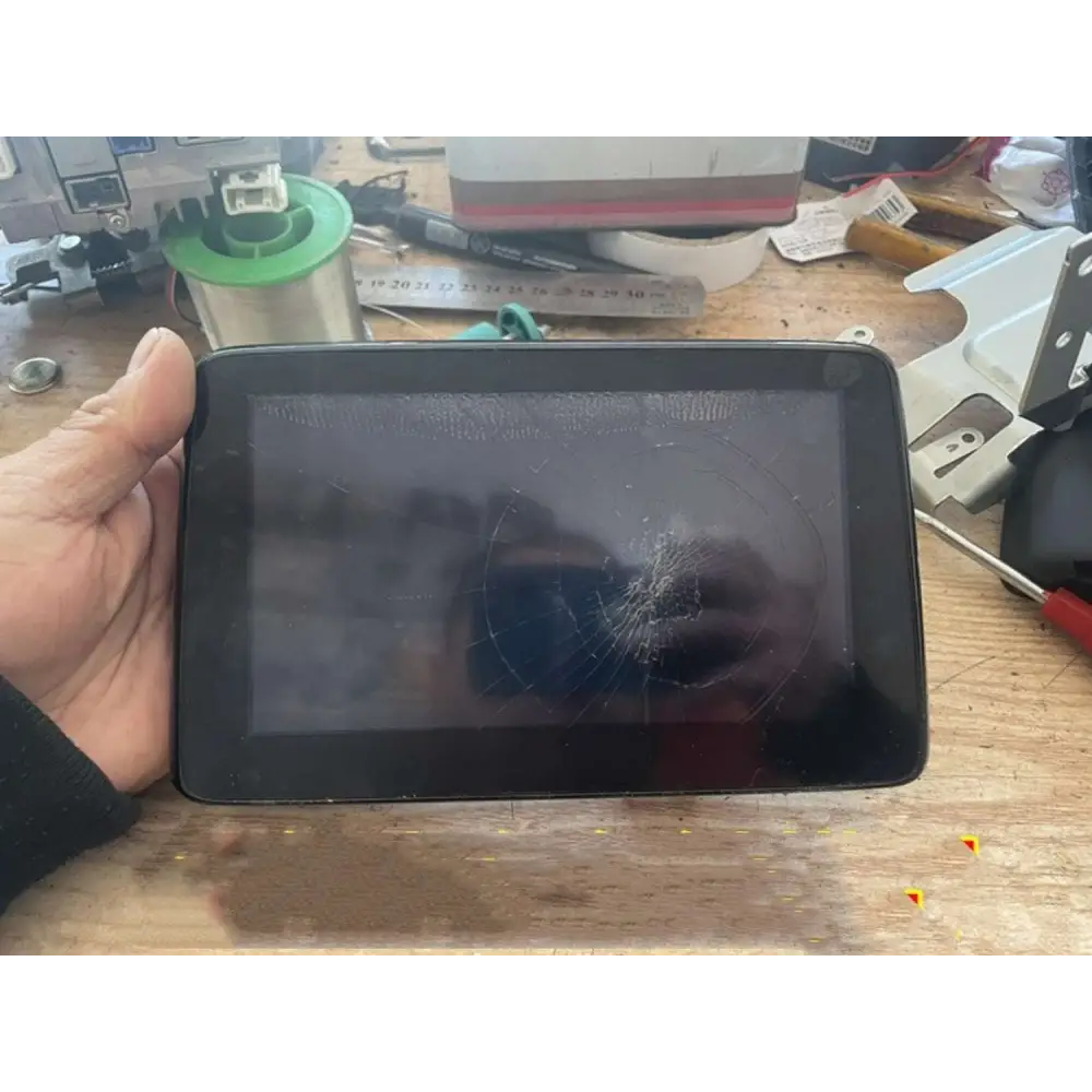 Black original car exterior tablet with cracked screen held in hand for screen replacement touch use