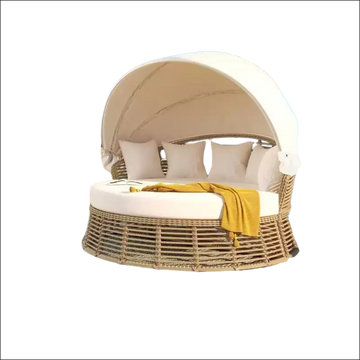 Beige outdoor patio rattan round daybed with canopy and white cushions accented by yellow throw blanket sofa bed style