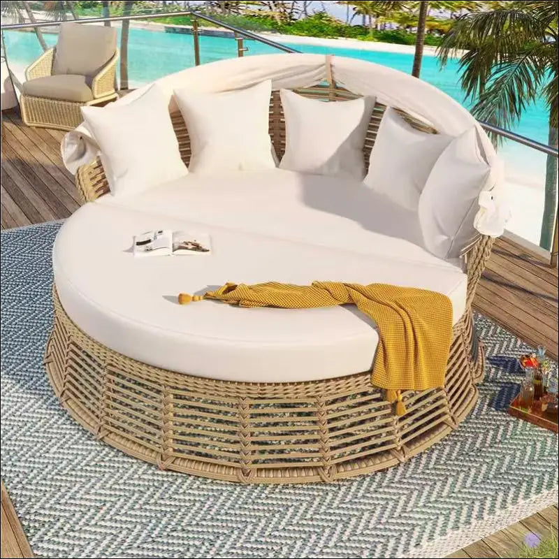 Beige wicker outdoor patio rattan round daybed sofa bed with white cushions and mustard yellow throw blanket