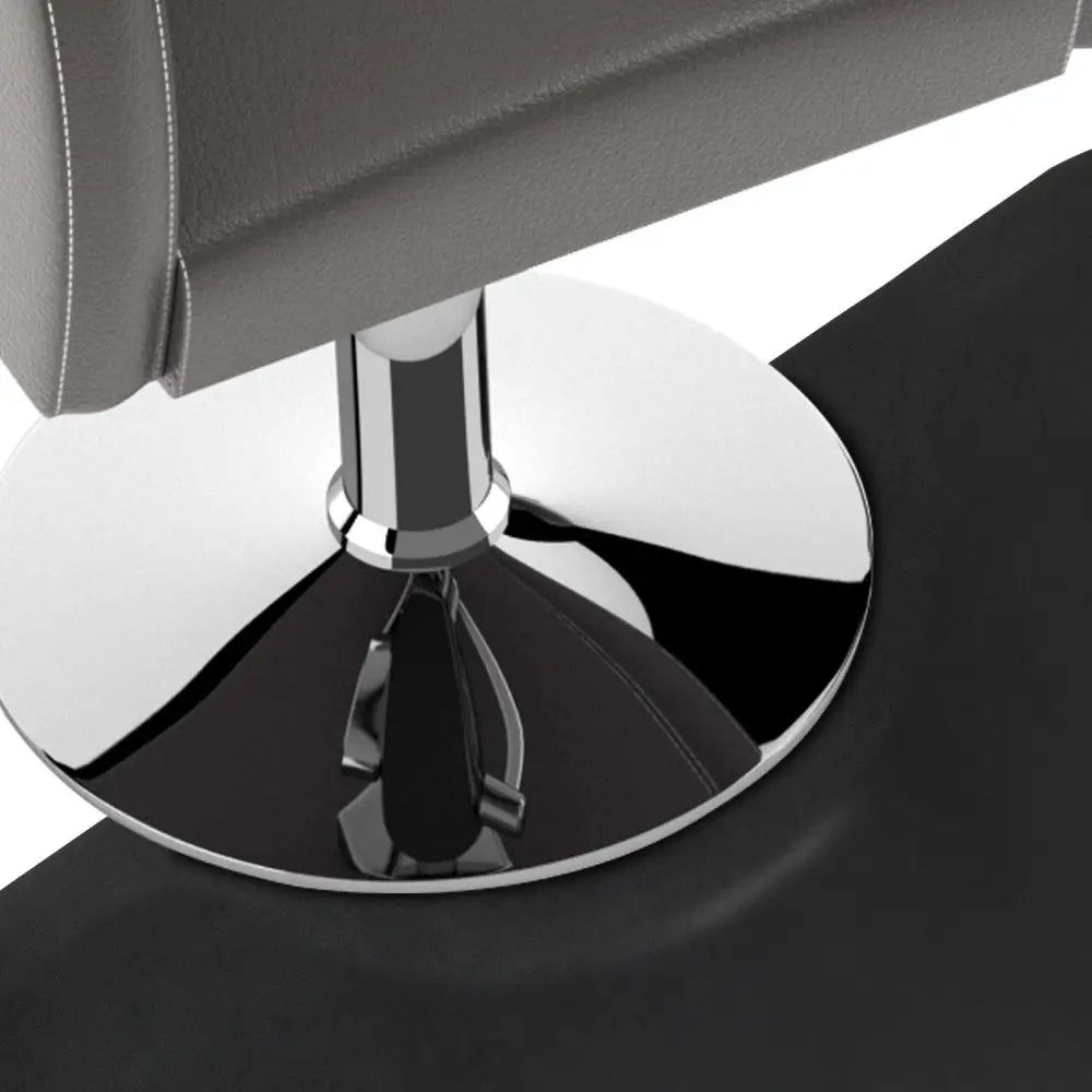 Gray leather salon chair with polished chrome base and circular footrest on high-density foam black semi-circular salon mat featuring outer circle design