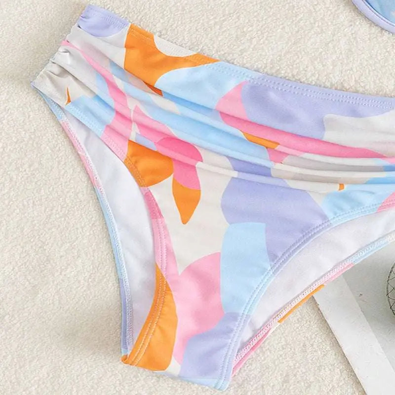Pastel abstract bikini fashion split swimsuit with swim bottoms featuring playful leaf print in soft pink blue and orange hues