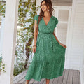 A woman wearing a green floral summer dress with ruffle cap sleeves and a cinched waist for summer dresses ruffle look