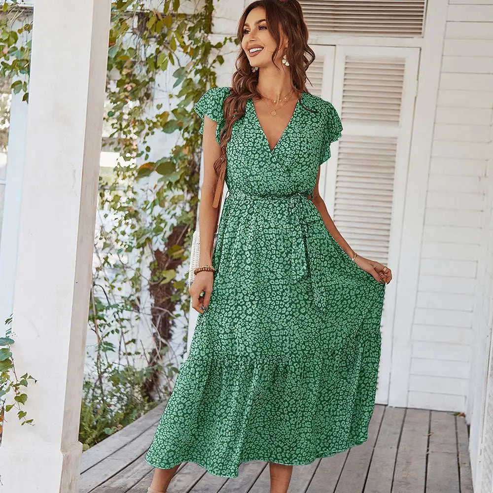 A woman wearing a green floral summer dress with ruffle cap sleeves and a cinched waist for summer dresses ruffle look