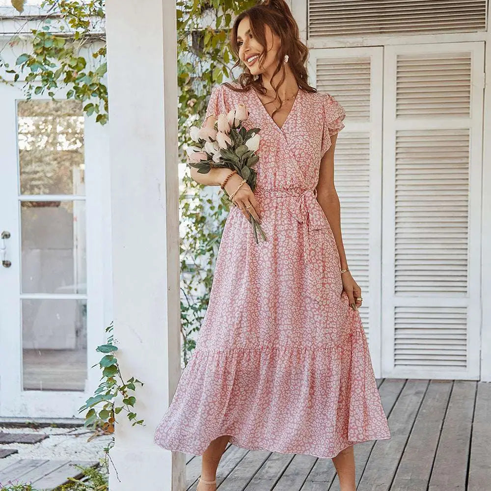 A flowing pink pastel floral summer dress with ruffle cap sleeves and a tiered skirt featuring white floral pattern