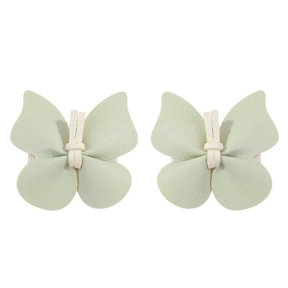 Pair of pale green leather butterfly bag clip children’s barrettes made from textured leather with cream fabric ties