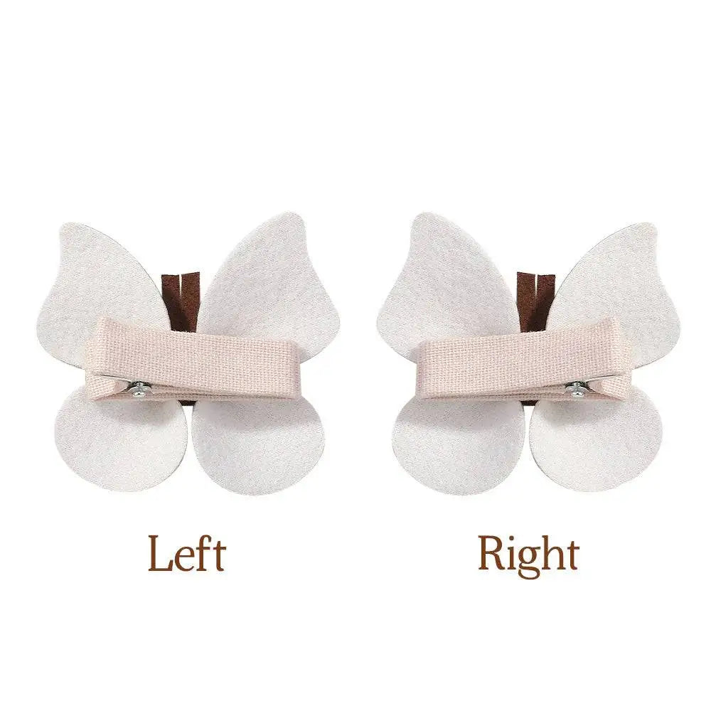 A pair of delicate white leather butterfly bag clip children’s barrettes with soft fabric wings and light pink ribbon band