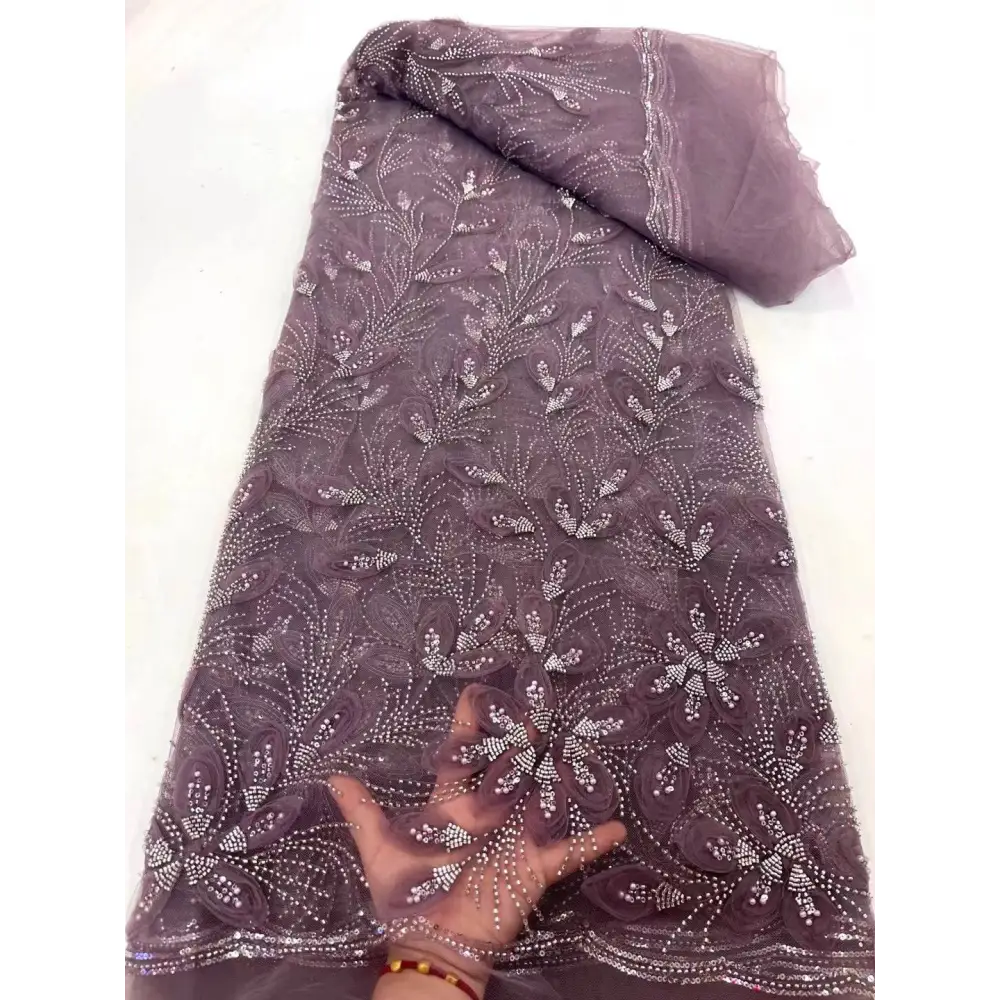 A delicate mauve peach ribbon flower beaded tulle lace fabric with intricate floral patterns and rhinestone embellishments