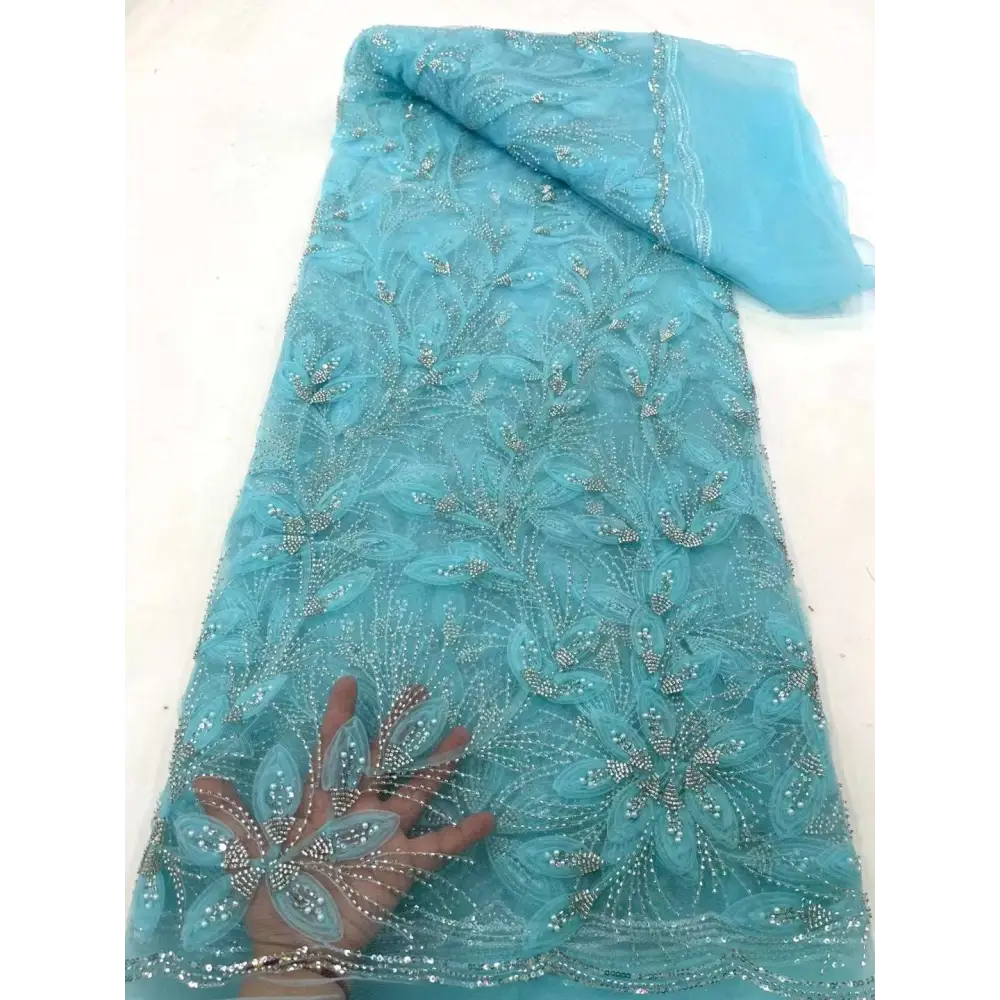 A delicate turquoise peach ribbon flower beaded tulle lace fabric with intricate floral patterns and silver beads