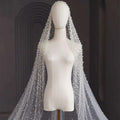 A delicate white pearl long luxury wedding veil with sheer flowing design and intricate beaded accents