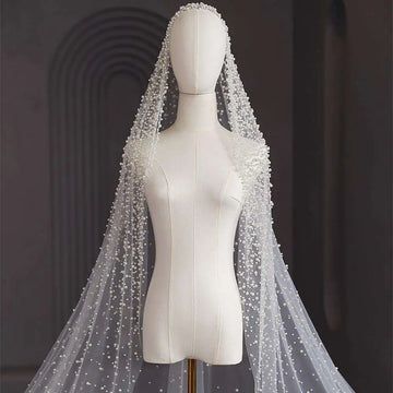 A delicate white pearl long luxury wedding veil with sheer flowing design and intricate beaded accents