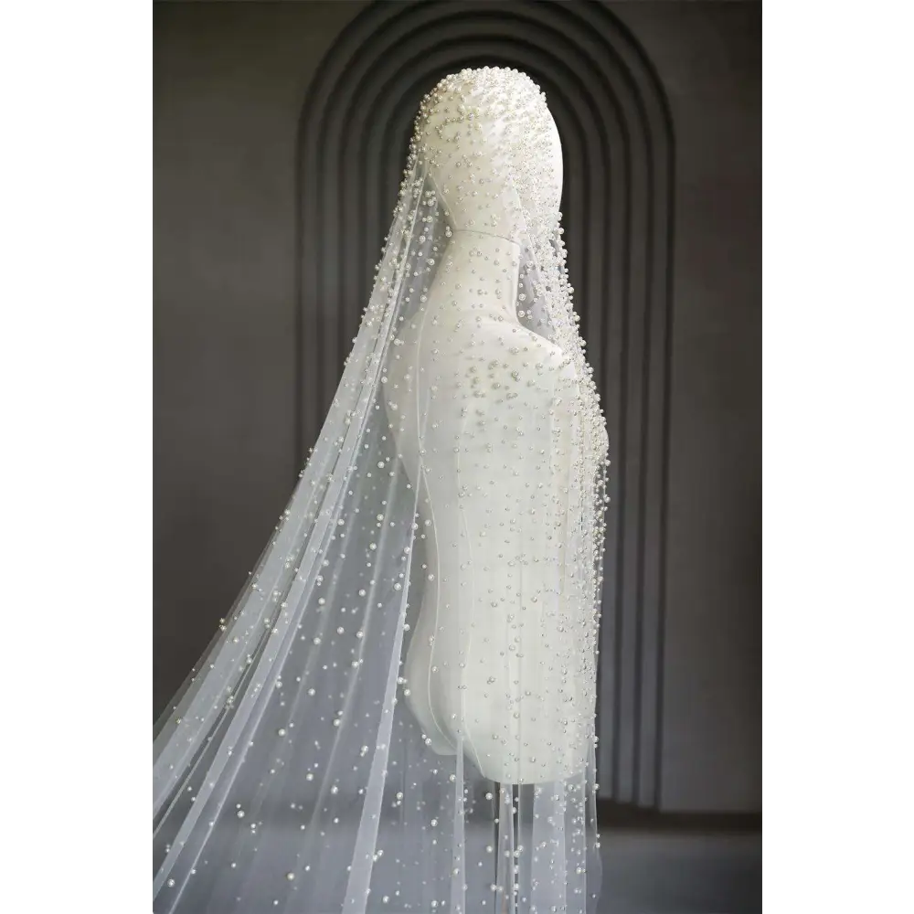 Delicate white pearl luxury wedding veil with sheer fabric and intricate beaded accents cascading down its length