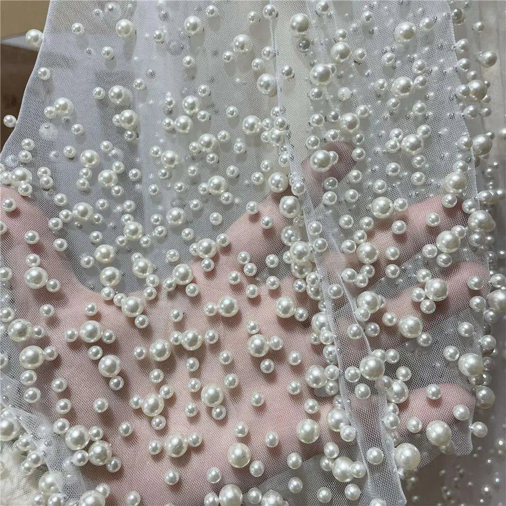A luxury wedding veil in delicate white sheer fabric with varying sized pearl beaded accents for elegant bridal wear