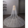 A delicate white pearl wedding veil with subtle beading and a flowing train in long bridal cathedral style