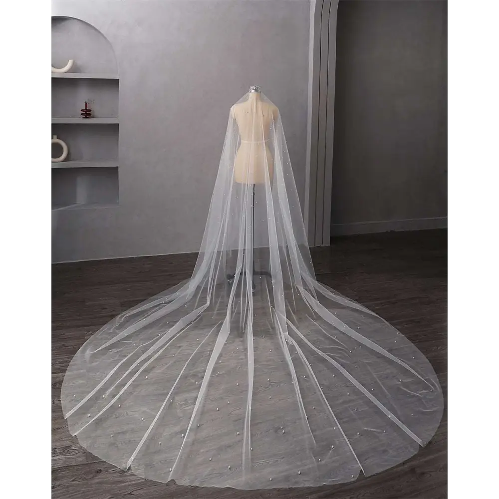A delicate white pearl wedding veil with subtle beading and a flowing train in long bridal cathedral style