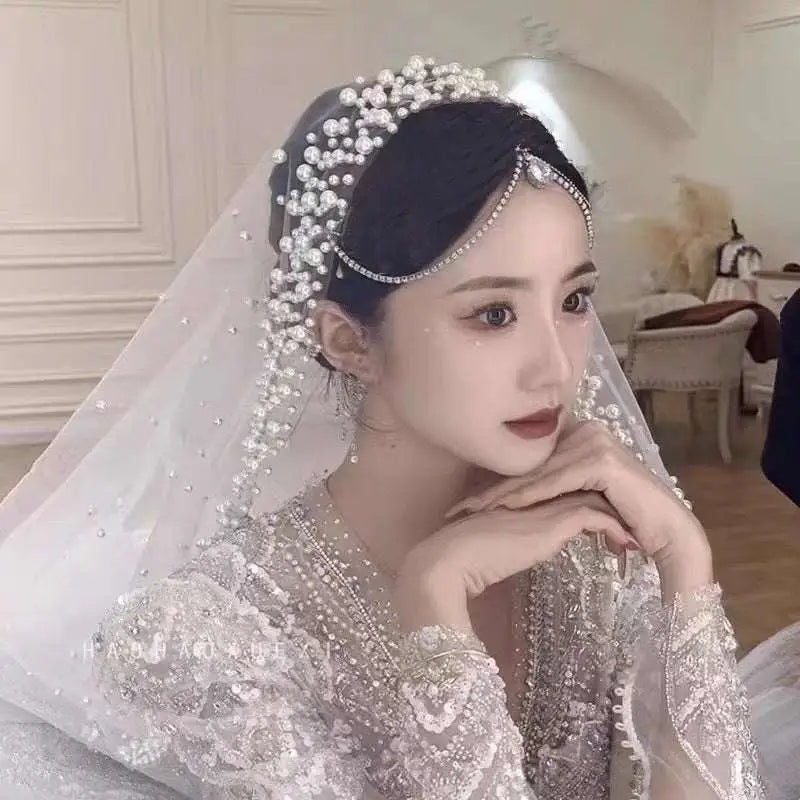 A sparkling silver beaded bridal headpiece with pearls and rhinestones complements a white pearl wedding veil long bridal cathedral