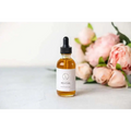 A clear glass bottle with black dropper containing amber belly oil for personalized ashley pampering natural skincare mom gift