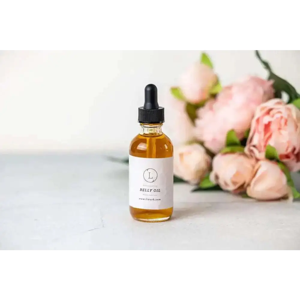 A clear glass bottle with black dropper containing amber belly oil for personalized ashley pampering natural skincare mom gift
