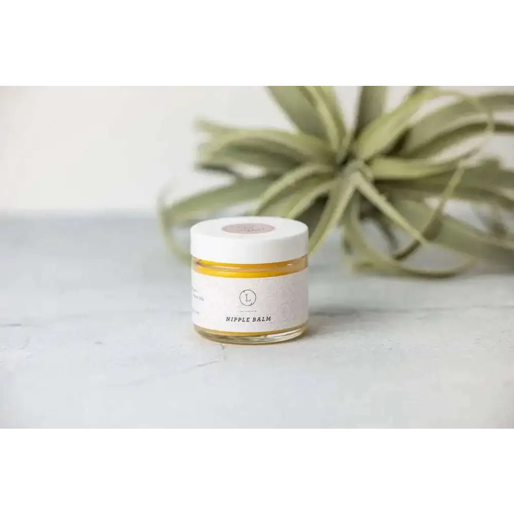 A small glass jar with white lid containing golden-yellow nipple balm for personalized Ashley pampering natural skincare mom gift