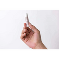 A sleek white lip balm tube with a minimalist label and soft pink text held gently as a personalized ashley pampering natural skincare mom gift