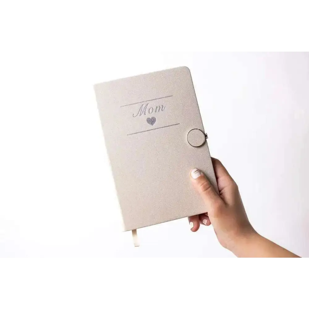 A soft beige textured notebook embossed with mom and a silver heart for the personalized ashley pampering skincare mom gift