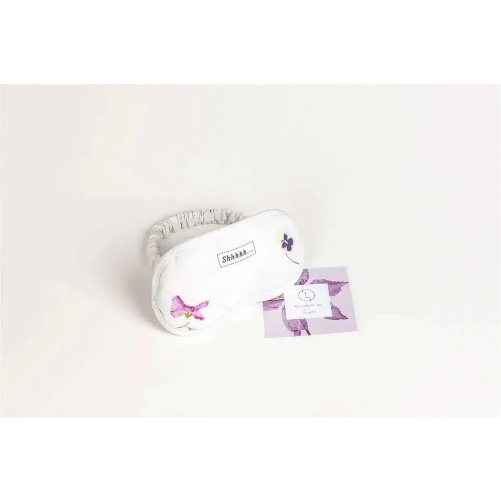 White sleep mask with embroidered purple flowers and gray strap for personalized ashley pampering skincare mom gift