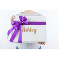 A shimmering silver gift box with a purple satin ribbon and personalized gold foil name for a skincare mom gift