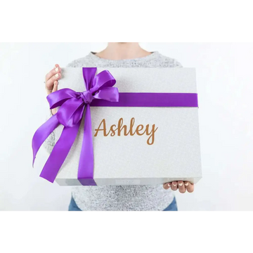A shimmering silver gift box with a purple satin ribbon and personalized gold foil name for a skincare mom gift