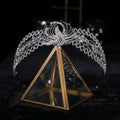 A sparkling silver rhinestone crown luxury bridal headdress with a phoenix motif on a gold triangular glass stand