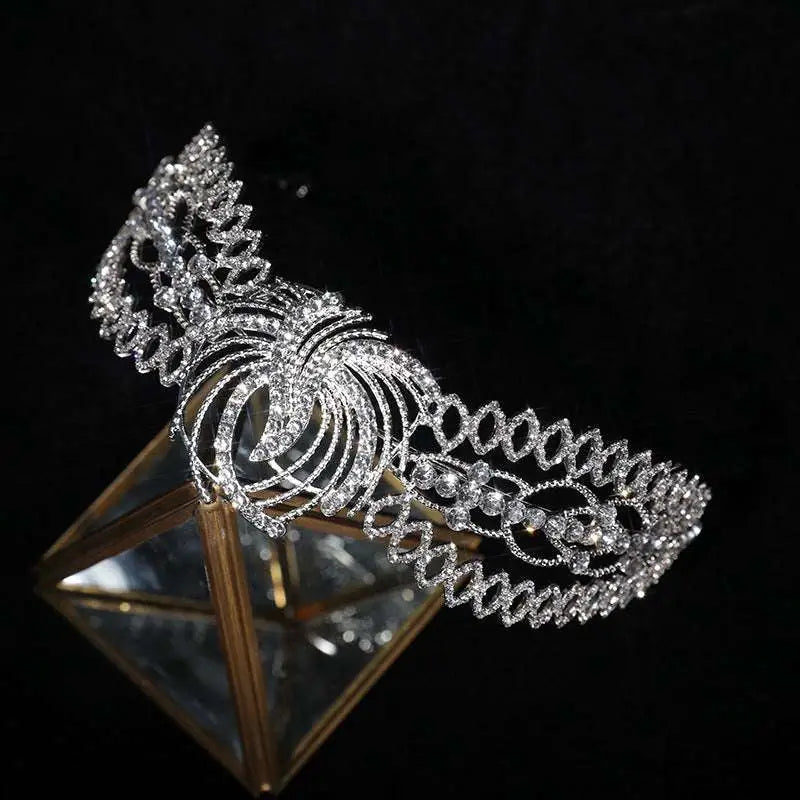 A sparkling silver rhinestone crown luxury bridal headdress with intricate crystal phoenix motif and ornate swirling design