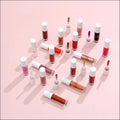 A collection of colorful transparent glass Phoera high shine crystal lip gloss bottles with white caps and red branding