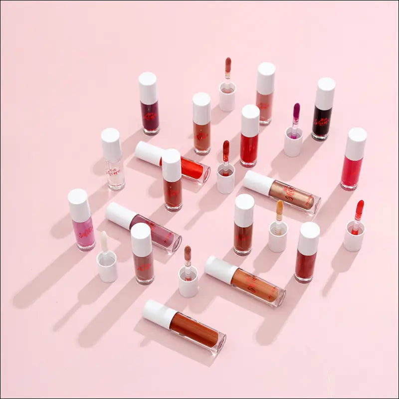 A collection of colorful transparent glass Phoera high shine crystal lip gloss bottles with white caps and red branding