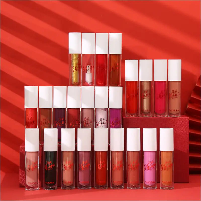 A collection of phoera high shine crystal lip glosses in clear tubes with white caps in shades from nude to deep red for luxury women’s fashion