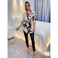 A long-sleeved printed belted shirt dress with a bold black white and gold chain-link pattern and cinched waist