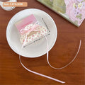 A delicate white hair tie with pink polka dots and matching ribbon in a pastel pink box with lucky everyday label