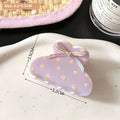 Pastel lavender small jaw clip adorned with pink butterfly floral patterns and a secure metallic ribbon bow