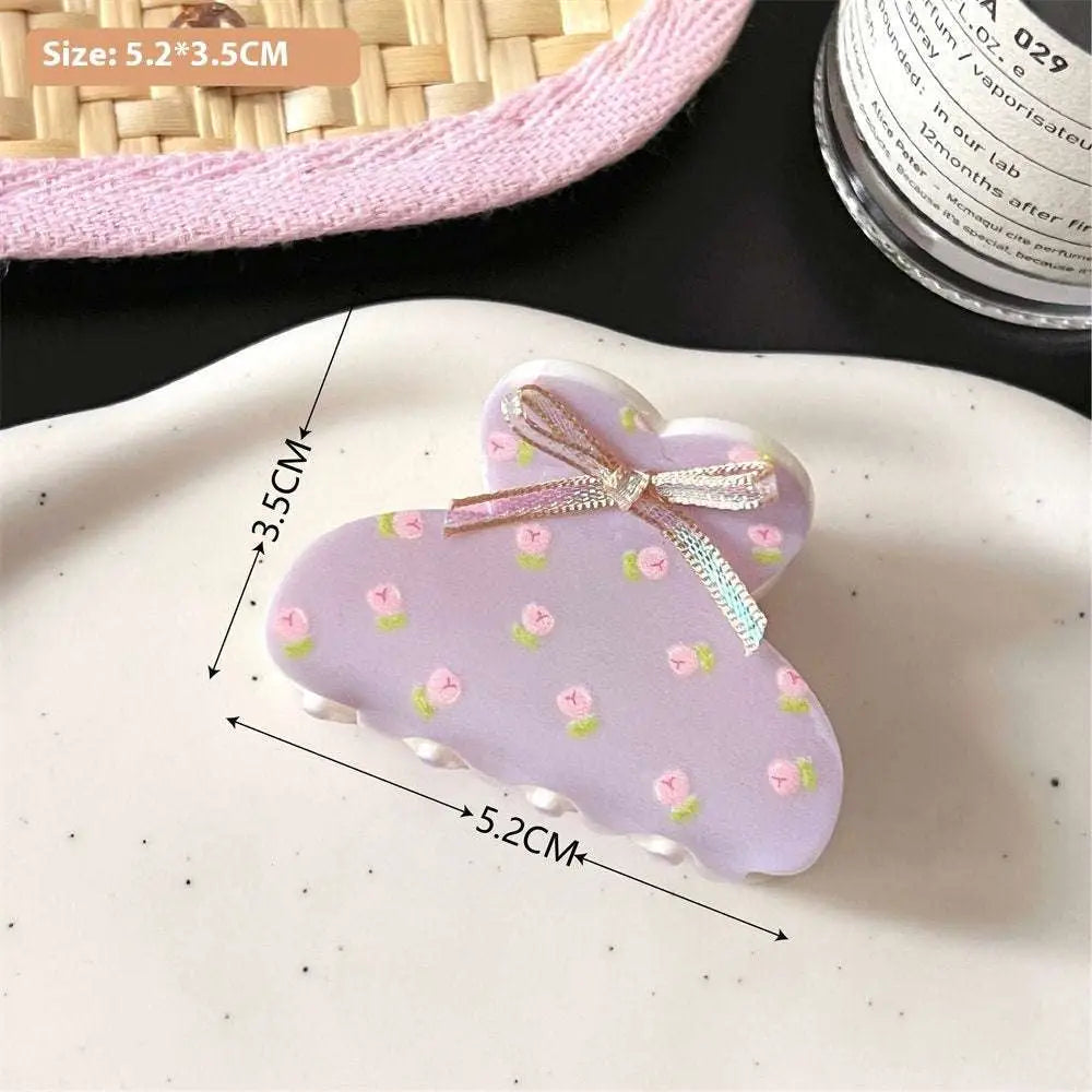 Pastel lavender small jaw clip adorned with pink butterfly floral patterns and a secure metallic ribbon bow