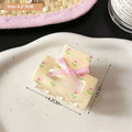 Cream-colored plastic small jaw clip with pink butterfly floral pattern and matching ribbon bow secure jaw clip