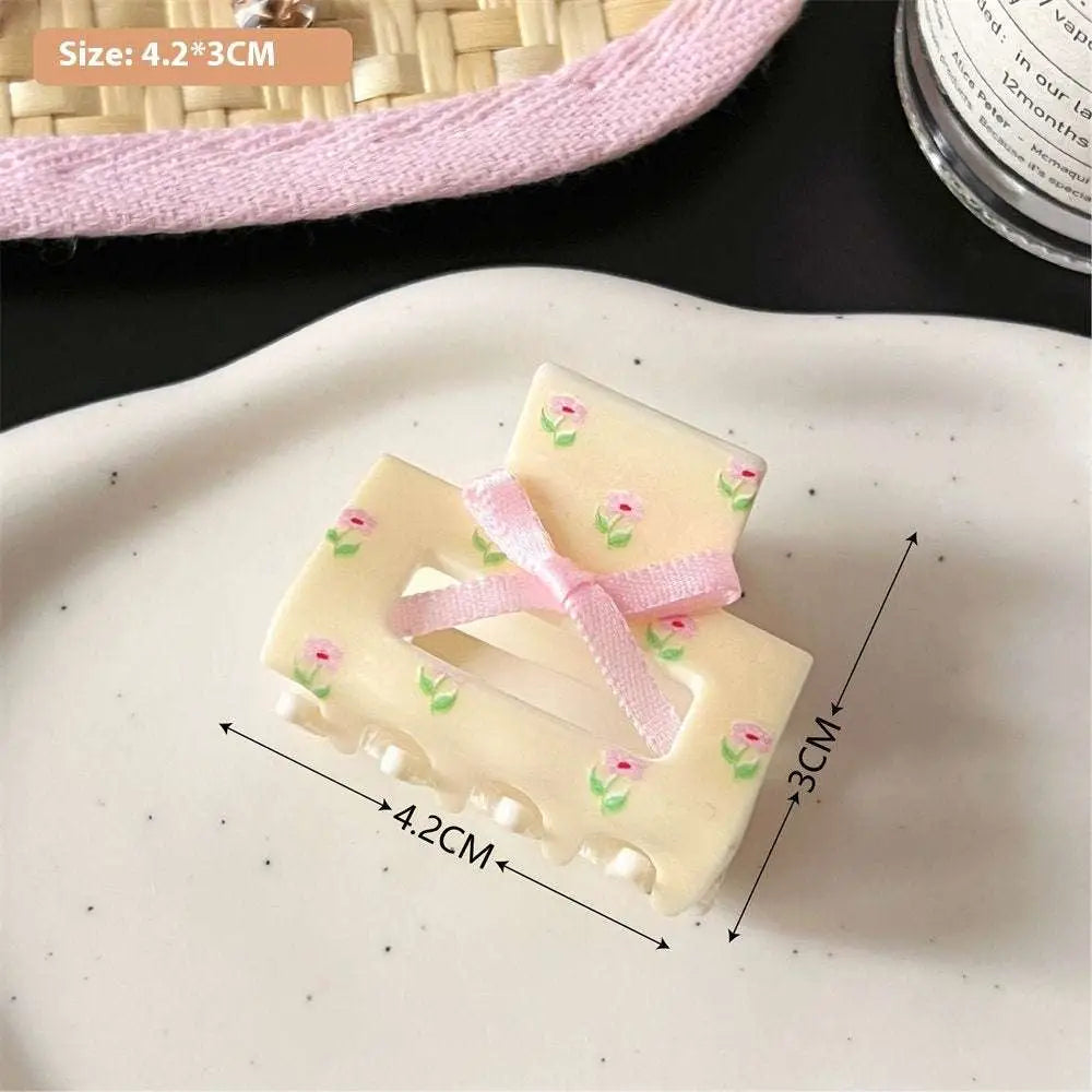 Cream-colored plastic small jaw clip with pink butterfly floral pattern and matching ribbon bow secure jaw clip