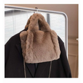 A pink faux fur chain plush handbag with soft plush texture in taupe color hanging on a coat rack