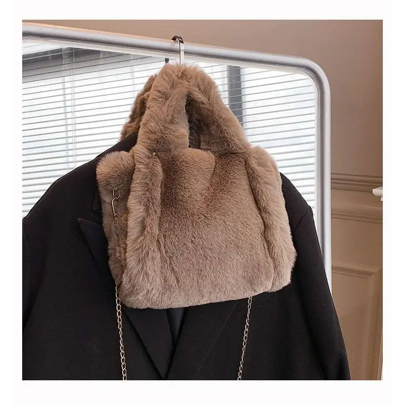 A pink faux fur chain plush handbag with soft plush texture in taupe color hanging on a coat rack